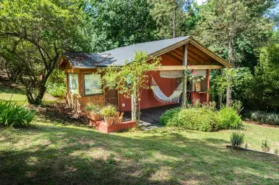 a small red cabin in the middle of a yard at Akapana Suites in La Cumbrecita