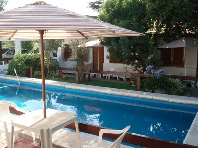a patio umbrella and chairs next to a swimming pool at El Agora in Villa General Belgrano