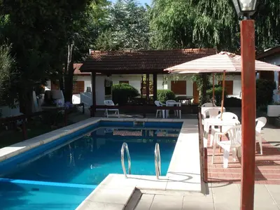a swimming pool with a table and an umbrella at El Agora in Villa General Belgrano