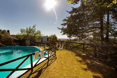 a swimming pool next to a fence with the sun at Hotel Panorama in La Cumbrecita