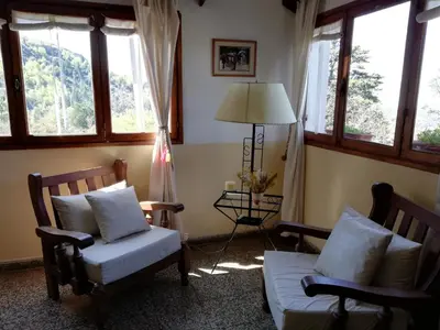 a living room with two chairs and a lamp and windows at Hotel Panorama in La Cumbrecita