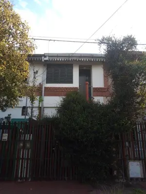 a white house with a gate and a fence at La Escalerita- Estadio Kempes in Cordoba