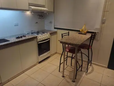 a kitchen with a stove and a table with stools at La Escalerita- Estadio Kempes in Cordoba