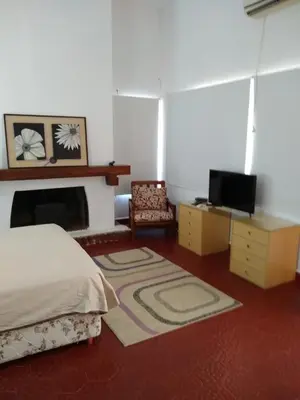 a bedroom with a bed and a fireplace and a chair at Casita Misol con piscina exclusiva y 100 mts del rio in Villa Carlos Paz