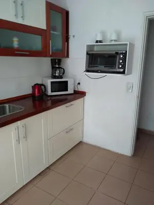 a kitchen with white cabinets and a microwave at Casita Misol con piscina exclusiva y 100 mts del rio in Villa Carlos Paz