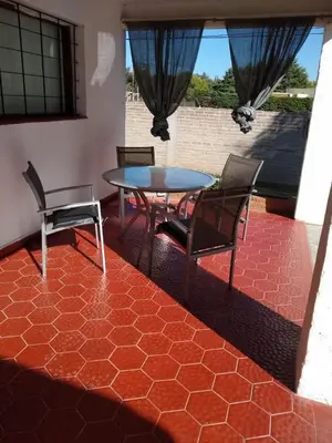 a patio with a table and chairs on a red floor at Casita Misol con piscina exclusiva y 100 mts del rio in Villa Carlos Paz