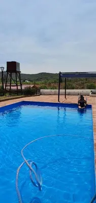 a large blue swimming pool with a hose at Cabañas La Escondida Casa De campo in San Antonio de Arredondo