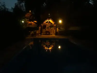 a house at night with a reflection in a pool at Cabañas La Escondida Casa De campo in San Antonio de Arredondo