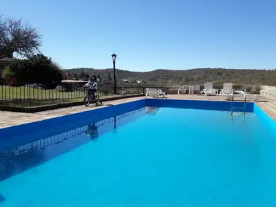 a person riding a bike next to a blue swimming pool at Cabañas La Escondida Casa De Campo 2 in San Antonio de Arredondo
