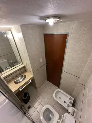 a bathroom with a toilet and a sink and a mirror at Apart Hotel Bari in Cordoba