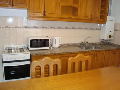 a kitchen with a sink and a stove and a microwave at Departamento Andino in Río Cuarto