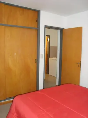 a bedroom with a red bed and wooden doors at Departamento Andino in Río Cuarto