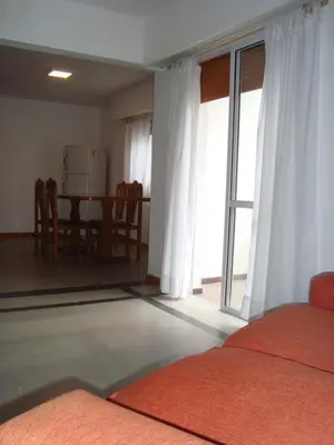 a room with two beds and a table and a window at Departamento Andino in Río Cuarto