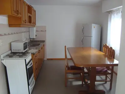 a kitchen with a table and a white refrigerator at Departamento Andino in Río Cuarto