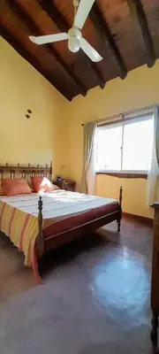 a bedroom with a large bed with a ceiling fan at Las Casitas, cabañas & suites in Pincén