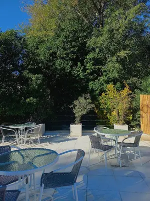 an outdoor patio with tables and chairs and trees at Posada Faro Serrano in Villa General Belgrano