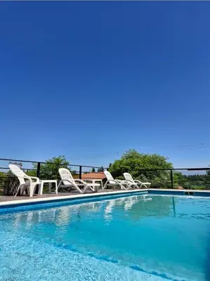 a large swimming pool with chairs and a table at Posada Faro Serrano in Villa General Belgrano