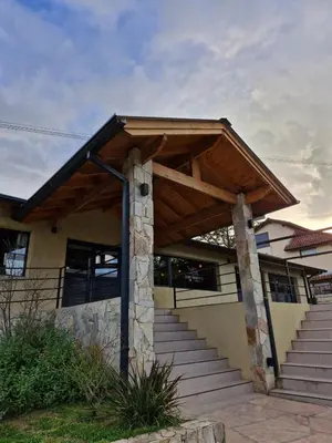 a house with a wooden roof and stairs at Posada Faro Serrano in Villa General Belgrano