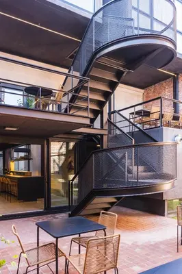 a spiral staircase in a building with a table and chairs at Faz Hostel Boutique in Cordoba