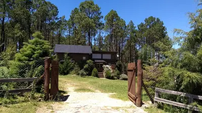 a house with a gate in front of a yard at LA LINDA - Cabaña de Montaña in Villa Berna