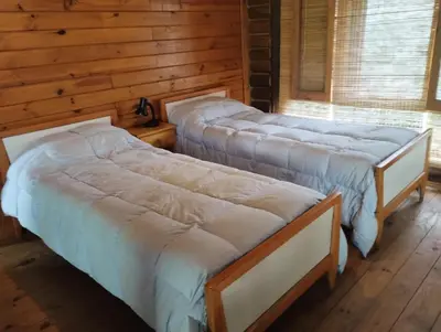 two beds in a room with wooden walls at LA LINDA - Cabaña de Montaña in Villa Berna