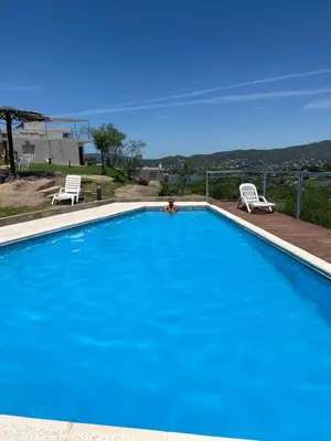a large blue swimming pool with two chairs and a person in it at Vista del Lago in Villa Carlos Paz