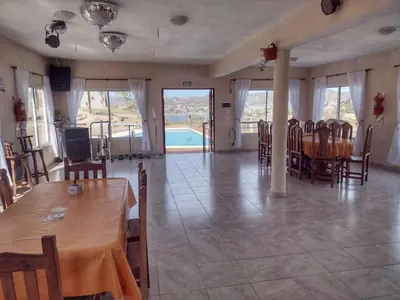 a dining room with a table and chairs and a pool at Vista del Lago in Villa Carlos Paz