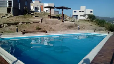 a swimming pool with blue water in front of a building at Vista del Lago in Villa Carlos Paz