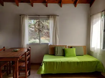 a bedroom with a bed and a table and a window at Espejo de Hadas - Terrafirme in Villa Yacanto