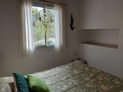 a bedroom with a bed and a window at Espejo de Hadas - Terrafirme in Villa Yacanto