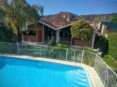 a swimming pool in front of a house at Cabañas Bosque in Villa Carlos Paz