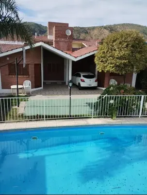 a swimming pool in front of a house at Cabañas Bosque in Villa Carlos Paz