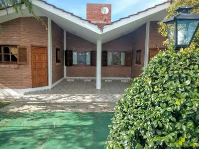 a brick house with a large green bush in front of it at Cabañas Bosque in Villa Carlos Paz