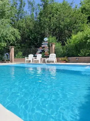a swimming pool with two white chairs and a fountain at La Mexicana - Alta Gracia in Alta Gracia