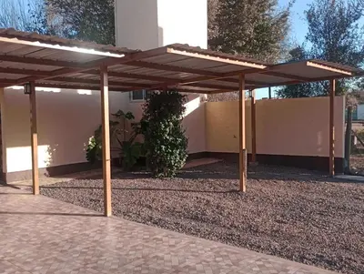 a wooden pergola in a yard next to a building at APART DEUFELL in Embalse