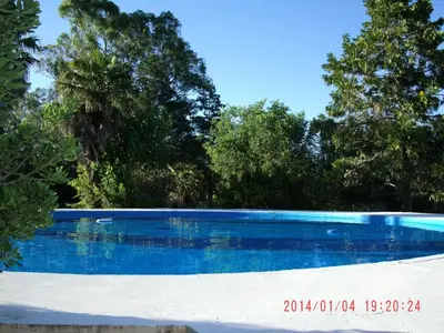 a blue swimming pool with trees in the background at Hotel de Campo Posada la Esperanza in Río Cuarto