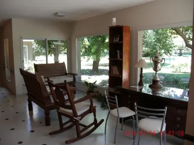 a living room with a desk and chairs and windows at Hotel de Campo Posada la Esperanza in Río Cuarto