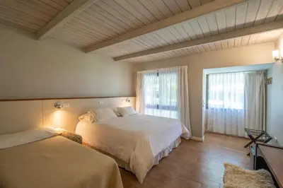 a bedroom with two beds and a large window at Atelier Hotel de Charme in Villa General Belgrano