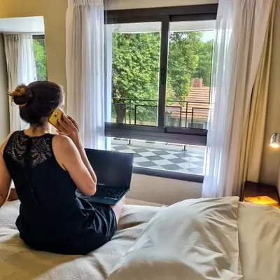 a woman sitting on a bed talking on a cell phone at Atelier Hotel de Charme in Villa General Belgrano