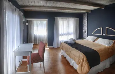 a bedroom with a bed and a table and a desk at Atelier Hotel de Charme in Villa General Belgrano
