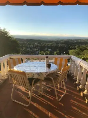 a table and chairs on a balcony with a view at CASA CON VISTA A LAS SIERRAS in Villa Carlos Paz