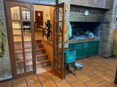 a room with a brick fireplace and a room with shelves at CASA CON VISTA A LAS SIERRAS in Villa Carlos Paz