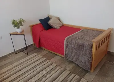 a bedroom with a bed with red sheets and a table at Complejo Serena in Santa Rosa de Calamuchita