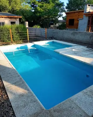 a swimming pool with blue water in a backyard at Complejo Serena in Santa Rosa de Calamuchita