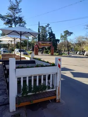 a white fence with an umbrella and flowers at HolaViajerosVGB in Villa General Belgrano