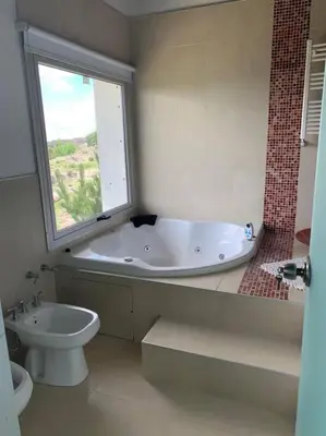 a bathroom with a tub and a toilet and a window at La Cumbrecita ,Casona super Lujo . in La Cumbrecita