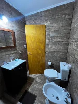 a bathroom with a sink and a toilet and a yellow door at Complejo LA MERLINA in Merlo