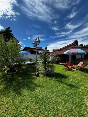 a yard with chairs and an umbrella and a house at Complejo LA MERLINA in Merlo