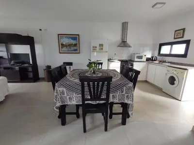 a dining room table with chairs and a kitchen at Complejo Claret, Departamentos a metros de Sanatorio Allende y Hospital Privado Cerro in Cordoba