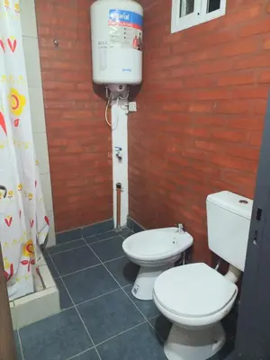 two toilets in a bathroom with a red brick wall at El Atardecer in Cortaderas